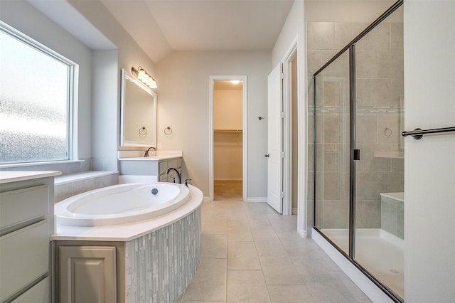 bathroom featuring a bath, a shower stall, a spacious closet, and tile patterned flooring