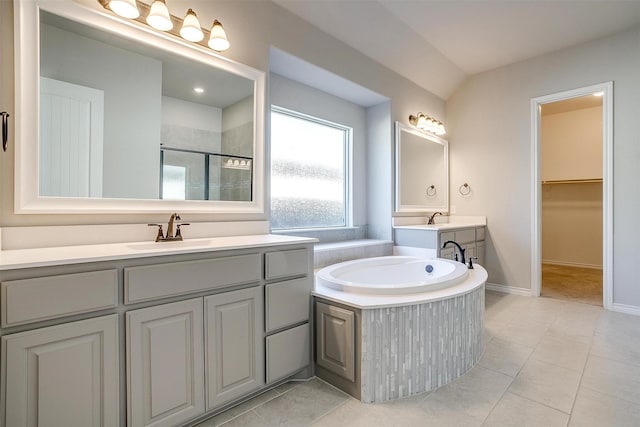 bathroom featuring a garden tub, a shower stall, a sink, and tile patterned floors