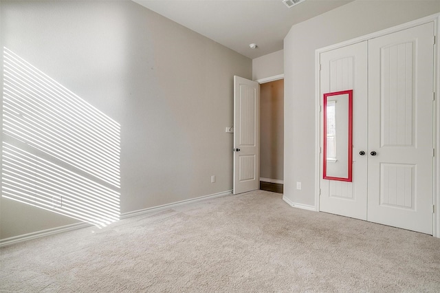 unfurnished bedroom featuring carpet floors, visible vents, and a closet