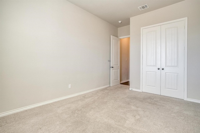 unfurnished bedroom with baseboards, carpet, visible vents, and a closet