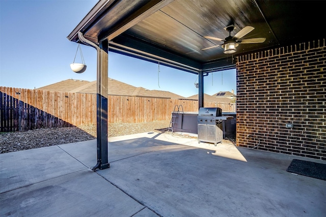 view of patio with area for grilling, a fenced backyard, and a ceiling fan