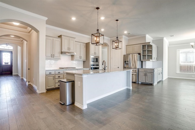 kitchen with under cabinet range hood, arched walkways, stainless steel appliances, and dark wood-style flooring