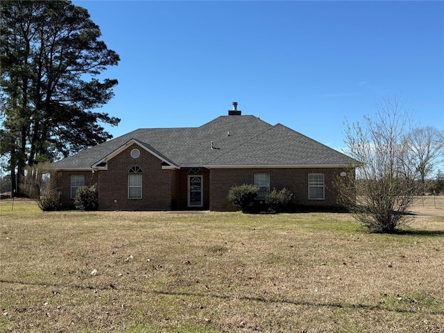 view of front facade featuring brick siding, a front lawn, and roof with shingles