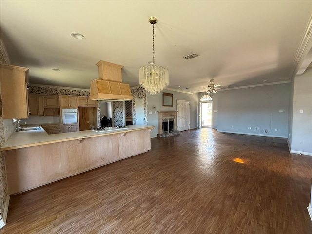 kitchen featuring a peninsula, white appliances, a sink, open floor plan, and light countertops