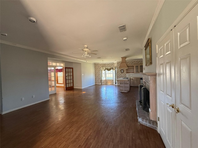 unfurnished living room with dark wood finished floors, a fireplace, crown molding, a ceiling fan, and baseboards