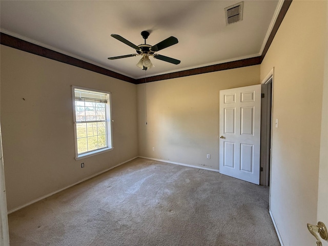 spare room with light colored carpet, visible vents, crown molding, and baseboards