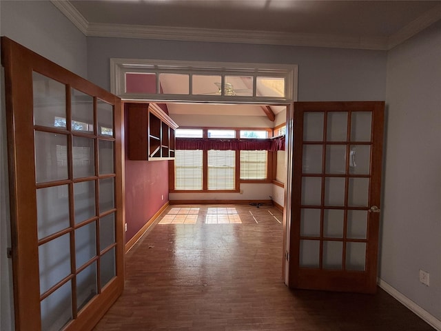 interior space with baseboards, crown molding, and wood finished floors