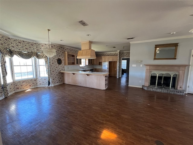 kitchen featuring a fireplace with raised hearth, open floor plan, a peninsula, custom exhaust hood, and a kitchen bar