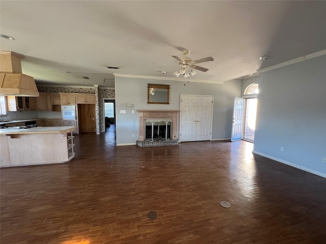 unfurnished living room featuring baseboards, ornamental molding, a fireplace with raised hearth, and dark wood-type flooring