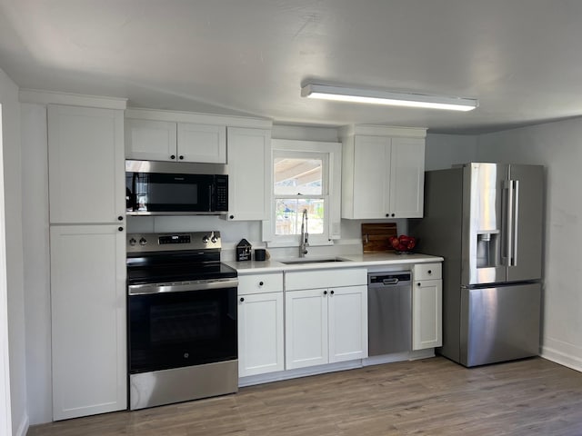 kitchen featuring white cabinetry, appliances with stainless steel finishes, light countertops, and a sink