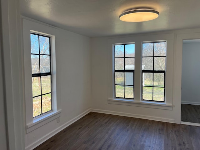 unfurnished room featuring dark wood-type flooring and baseboards