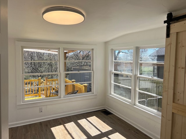 unfurnished sunroom featuring lofted ceiling, visible vents, and a barn door