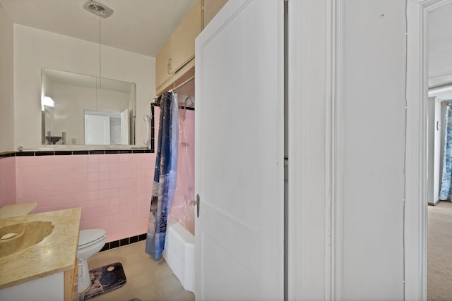 bathroom featuring toilet, visible vents, vanity, tile walls, and shower / bath combo