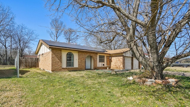 single story home featuring brick siding, roof mounted solar panels, fence, a garage, and a front lawn