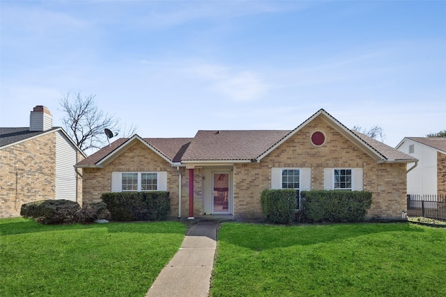 ranch-style home with brick siding, a front yard, and a shingled roof