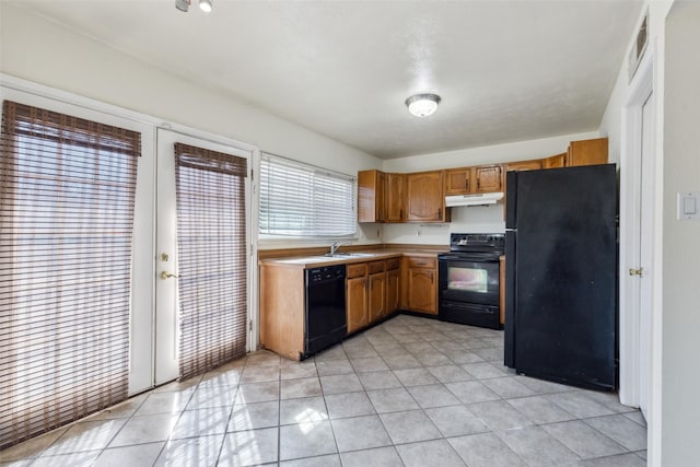 kitchen with visible vents, brown cabinetry, under cabinet range hood, light countertops, and black appliances