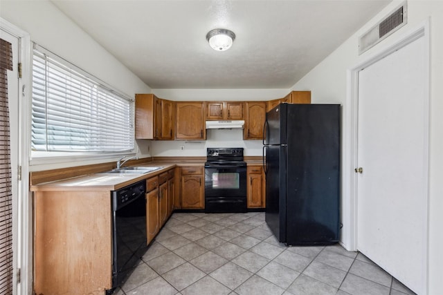 kitchen with light countertops, visible vents, a sink, under cabinet range hood, and black appliances