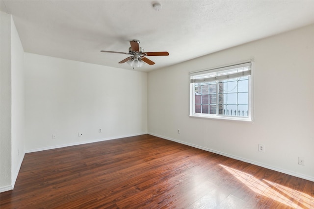 empty room with wood finished floors, a ceiling fan, and baseboards