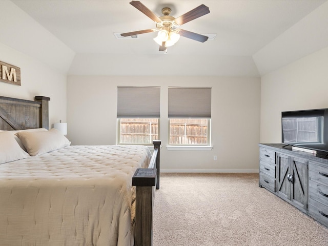 bedroom featuring lofted ceiling, light carpet, a ceiling fan, baseboards, and a tray ceiling