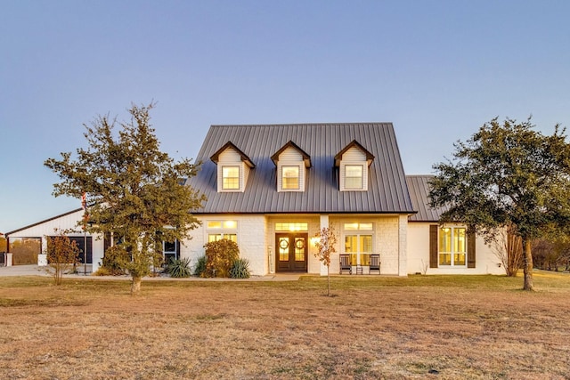 view of front of home with metal roof, french doors, and a yard