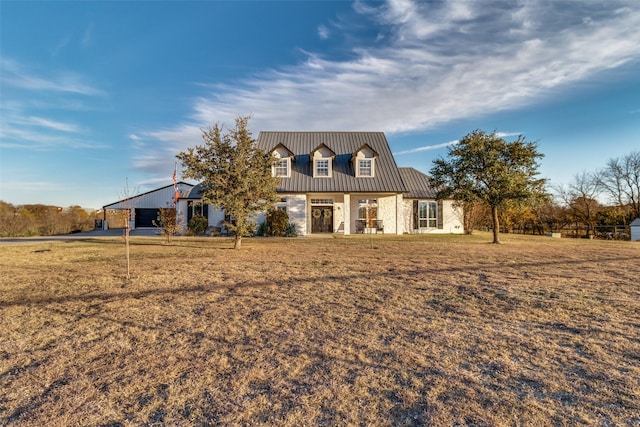 view of front of home with a standing seam roof, metal roof, and a front yard