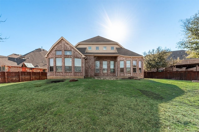 back of house with brick siding, fence, and a lawn