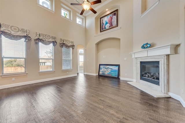 unfurnished living room featuring dark wood-type flooring, a premium fireplace, and plenty of natural light