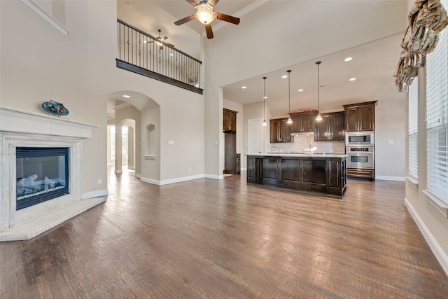 unfurnished living room with ceiling fan, dark wood-type flooring, and a premium fireplace