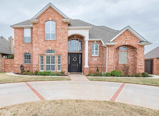 traditional-style home featuring brick siding and a shingled roof