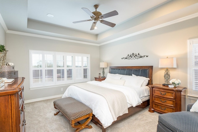 bedroom with baseboards, ornamental molding, a raised ceiling, and light colored carpet