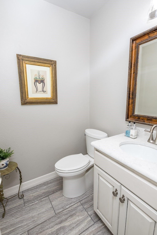 bathroom with toilet, wood tiled floor, baseboards, and vanity