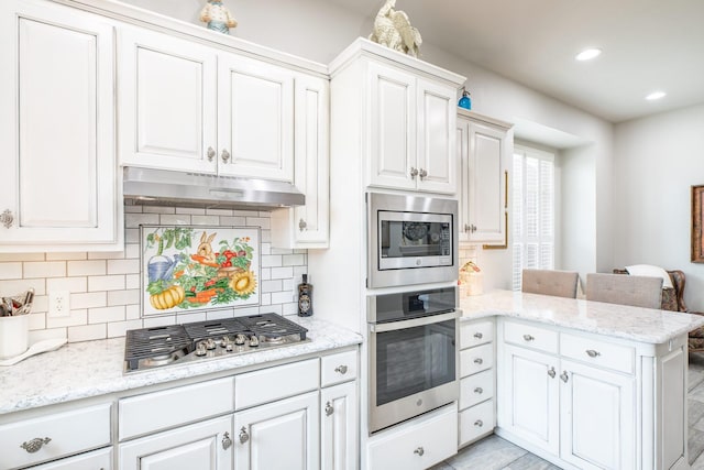 kitchen featuring a peninsula, appliances with stainless steel finishes, white cabinets, and under cabinet range hood