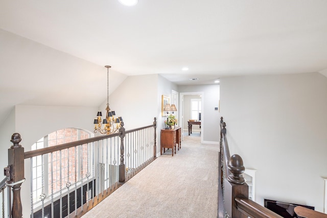 hall with carpet, an inviting chandelier, vaulted ceiling, an upstairs landing, and baseboards