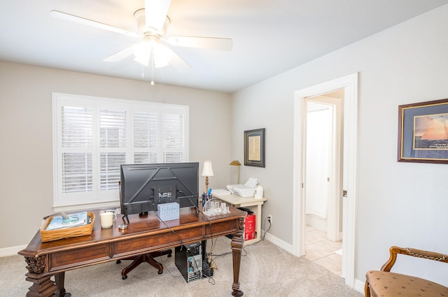 office space featuring baseboards, a ceiling fan, and light colored carpet