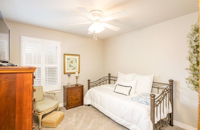 bedroom with a ceiling fan, light carpet, and baseboards