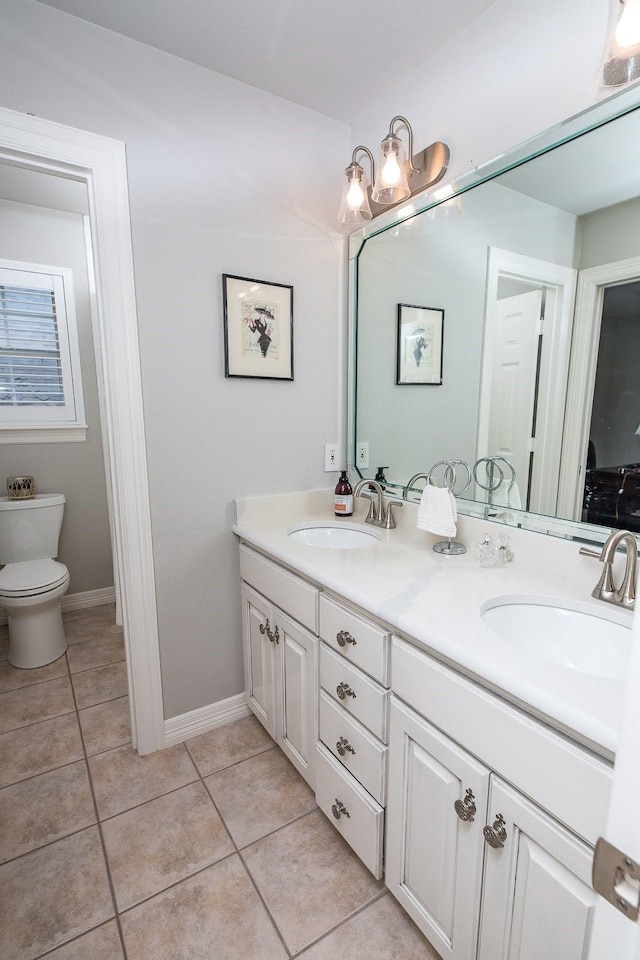 bathroom with double vanity, a sink, toilet, and tile patterned floors