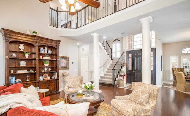 living room with a ceiling fan, dark wood-style floors, stairs, a healthy amount of sunlight, and ornate columns