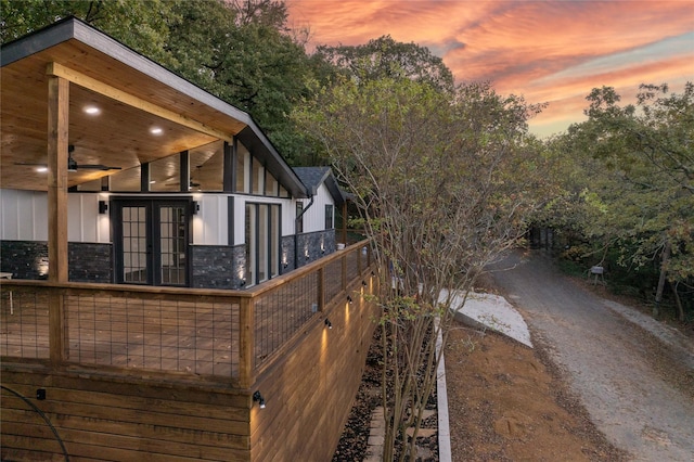 property exterior at dusk with stone siding and french doors