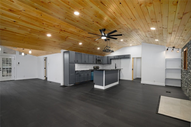 kitchen with decorative backsplash, stainless steel microwave, open floor plan, a center island, and gray cabinets