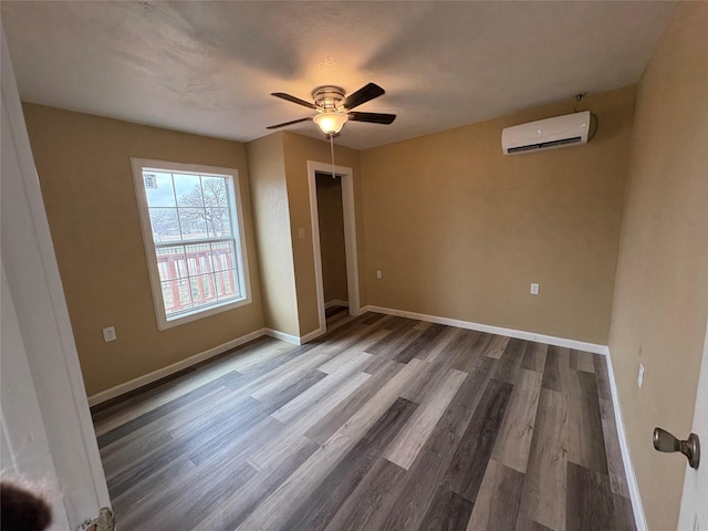 unfurnished bedroom with a wall unit AC, wood finished floors, a ceiling fan, baseboards, and a closet