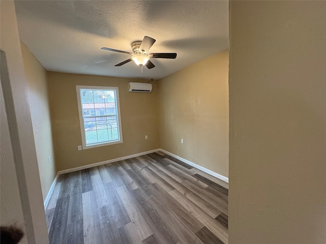 spare room with a textured ceiling, a wall mounted air conditioner, wood finished floors, and baseboards