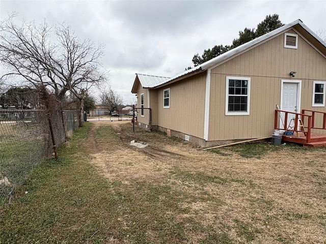 view of side of property with metal roof, a lawn, and fence