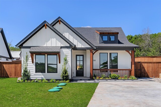 modern inspired farmhouse with a porch, fence, roof with shingles, a front lawn, and board and batten siding