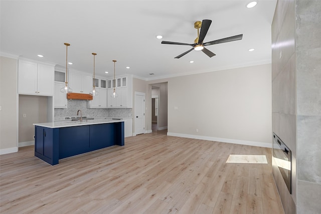 kitchen with white cabinets, glass insert cabinets, hanging light fixtures, light countertops, and a sink