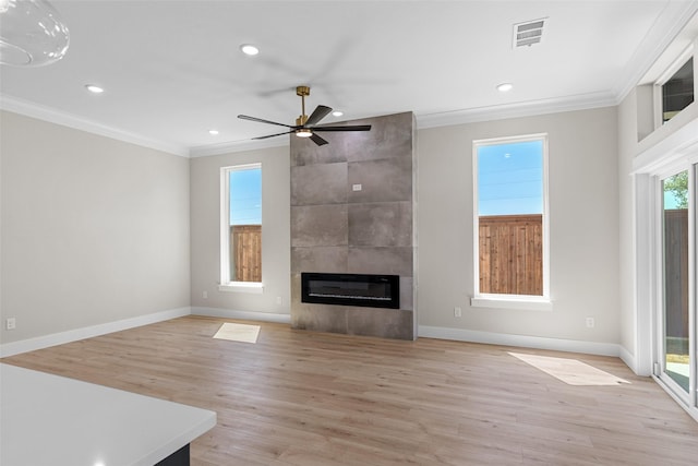 unfurnished living room with ornamental molding, a fireplace, light wood-style flooring, and visible vents