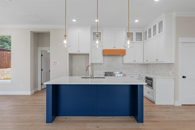 kitchen featuring white cabinetry, range hood, glass insert cabinets, and light countertops