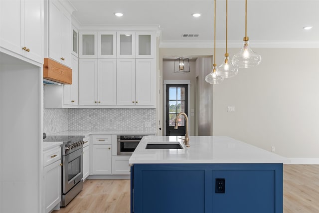 kitchen featuring decorative light fixtures, light countertops, appliances with stainless steel finishes, glass insert cabinets, and white cabinets