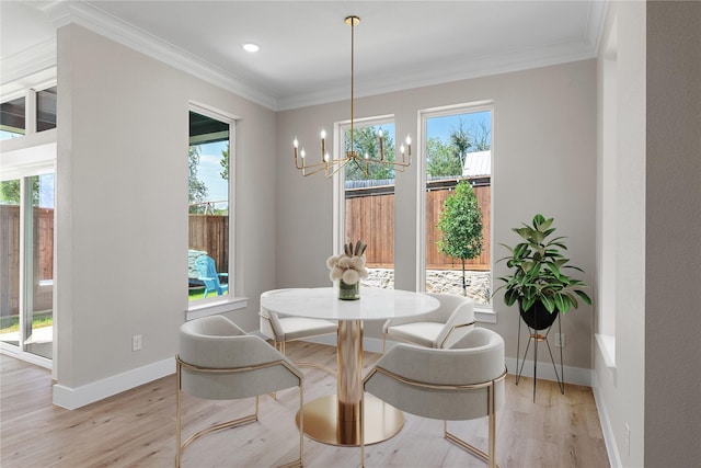 dining room with light wood-type flooring, baseboards, ornamental molding, and a notable chandelier