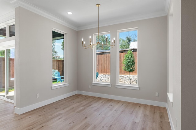 unfurnished dining area featuring a chandelier, ornamental molding, light wood-style flooring, and baseboards