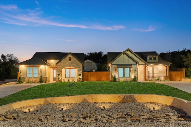 view of front of house with driveway, fence, board and batten siding, and a front yard